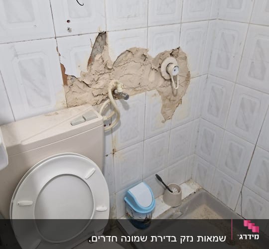חדר אמבטיה עם שירותים, מקלחת וקיר פגום